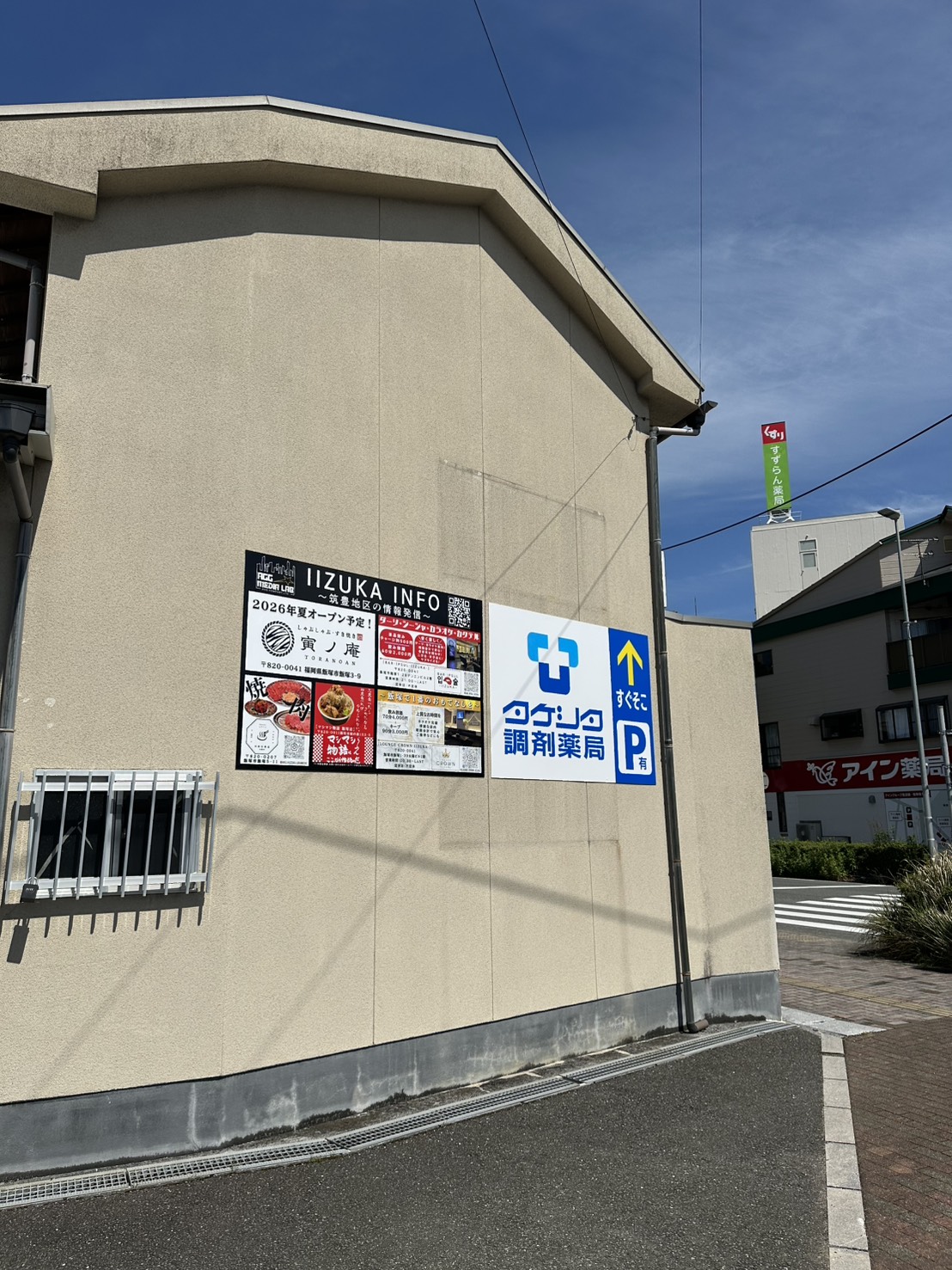 通りに面した本部事務所の壁面と地域情報の看板